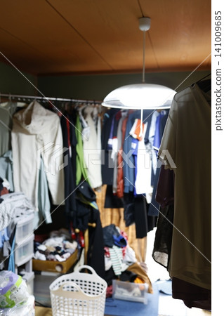 A messy, untidy room. A closet overflowing with clothes. Organizing clothes. A messy, untidy room. A closet overflowing with clothes. Organizing clothes. 141009685