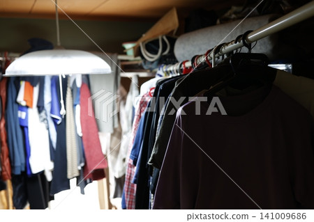 房間凌亂不堪。衣櫃裡塞滿了衣服。整理衣服。 房間凌亂不堪。衣櫃裡塞滿了衣服。整理衣服。 141009686