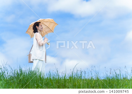 一位女士撐著陽傘在公園散步。 一位女士撐著陽傘在公園散步。 141009745
