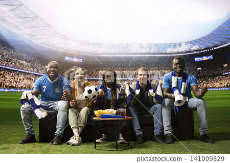 Happy soccer fans on couch cheering after goal, feeling like they are inside stadium. Cheerful football supporters together at home enjoying immersive match day during TV broadcast Happy soccer fans on couch cheering after goal, feeling like they are inside stadium. Cheerful football supporters together at home enjoying immersive match day during TV broadcast 141009829