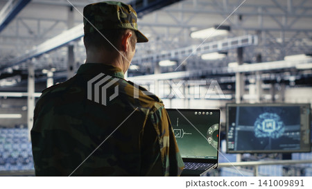 Military specialist in a military data center reviews radar software, watching for suspicious aerial activity and potential enemy threats. Military specialist in a military data center reviews radar software, watching for suspicious aerial activity and potential enemy threats. 141009891