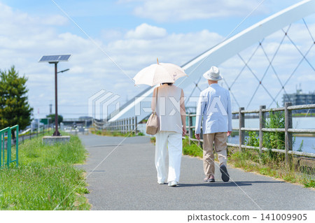 A parent and child walking along the riverbank; elderly, middle-aged. A parent and child walking along the riverbank; elderly, middle-aged. 141009905