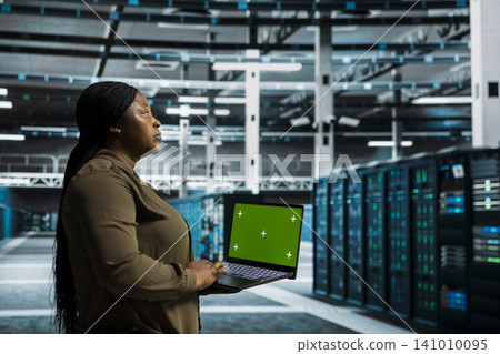 Data center administrator works with a chroma key laptop, using an editable screen to monitor anomaly detection. Data center administrator works with a chroma key laptop, using an editable screen to monitor anomaly detection. 141010095