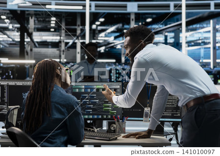 Server farm leader oversees an expert upgrading artificial intelligence systems and programming equipment for machine learning training. Server farm leader oversees an expert upgrading artificial intelligence systems and programming equipment for machine learning training. 141010097