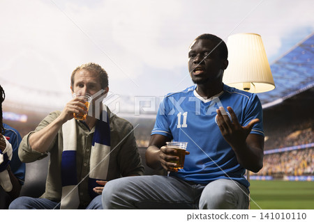 Close up of football supporters with beer cups watching match broadcast, feeling like being inside stadium. Soccer fans drink alcohol beverages while live game brings stadium energy into living room Close up of football supporters with beer cups watching match broadcast, feeling like being inside stadium. Soccer fans drink alcohol beverages while live game brings stadium energy into living room 141010110