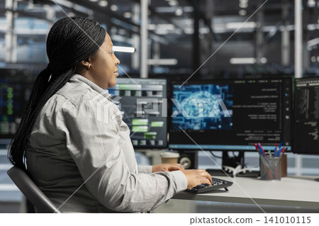 Server facility computing specialist applying AI neural network models technology. Woman working in data center working with AI programming tools on workstation, setting up specialized hardware. Server facility computing specialist applying AI neural network models technology. Woman working in data center working with AI programming tools on workstation, setting up specialized hardware. 141010115