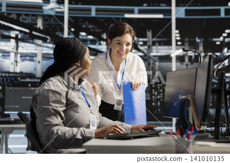 Smiling data center team works with digital devices while reviewing systems, scripts and server infrastructure. 141010135