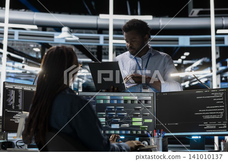 Computer scientist uses a PC in a data center to visualize interconnected AI neural networks and oversee information processing systems. 141010137