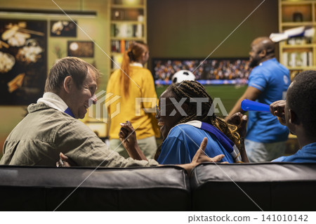 Close up of cheerful football fans sitting on couch and celebrating goal scored during match on TV. Supporters share happy reaction during win achieved by favorite team Close up of cheerful football fans sitting on couch and celebrating goal scored during match on TV. Supporters share happy reaction during win achieved by favorite team 141010142