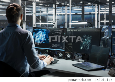 Data center technician uses a digital device in a data center to manage AI systems and optimize server infrastructure. Data center technician uses a digital device in a data center to manage AI systems and optimize server infrastructure. 141010147