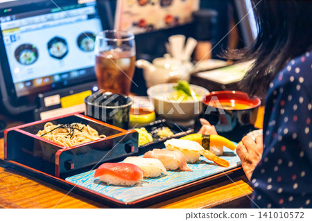 一位女士正在享用壽司蕎麥麵套餐。 一位女士正在享用壽司蕎麥麵套餐。 141010572
