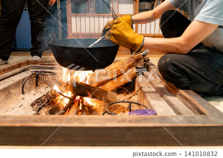 Iron pot simmering over a hearth Iron pot simmering over a hearth 141010832