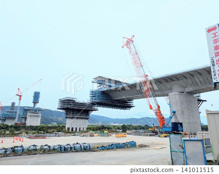 A large bridge is under construction; materials are being lifted by a crane. 141011515