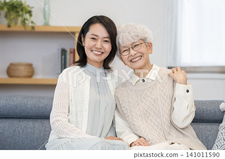 A portrait of a senior woman and a middle-aged woman, both smiling and looking at the camera, creating a mother-daughter image. A portrait of a senior woman and a middle-aged woman, both smiling and looking at the camera, creating a mother-daughter image. 141011590