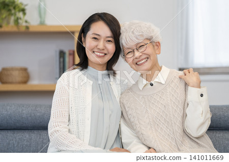 一位老年婦女和一位中年婦女面帶微笑地看著鏡頭,構成了一幅母女肖像。 一位老年婦女和一位中年婦女面帶微笑地看著鏡頭,構成了一幅母女肖像。 141011669