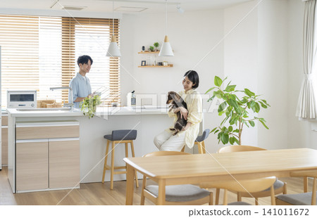 Image of life with a dog: A man and woman in their 30s relaxing at home with a miniature dachshund. Image of life with a dog: A man and woman in their 30s relaxing at home with a miniature dachshund. 141011672