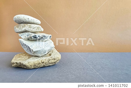 Stack of balancing stones arranged in a tower on a clean grey and beige background. Minimalist composition in wabi-sabi style with generous copy space. Concept of balance, stability, harmony Stack of balancing stones arranged in a tower on a clean grey and beige background. Minimalist composition in wabi-sabi style with generous copy space. Concept of balance, stability, harmony 141011702