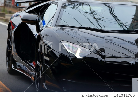 Image of a black Italian sports car driving through a city street. Image of a black Italian sports car driving through a city street. 141011769