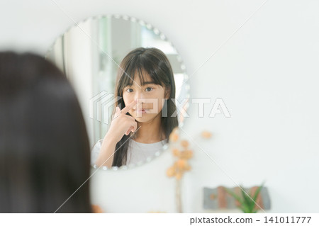 Elementary school girl looking in the mirror Elementary school girl looking in the mirror 141011777