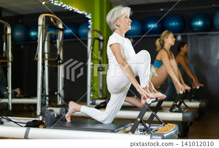 Mature woman actively doing Pilates exercises 141012010
