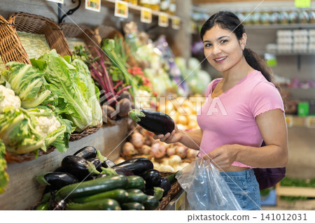 Adult woman choosing eggplants at vegetable shop Adult woman choosing eggplants at vegetable shop 141012031
