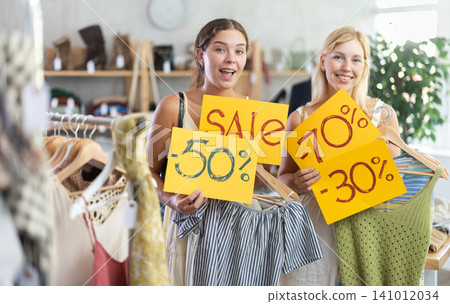 Young women holds yellow poster informing about discounts in store Young women holds yellow poster informing about discounts in store 141012034