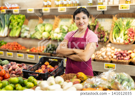Woman seller offering fresh vegetables and fruits in grocery store Woman seller offering fresh vegetables and fruits in grocery store 141012035