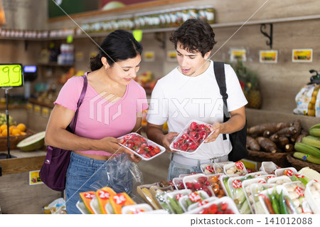 Couple choosing packaged vegetables and fruits at grocery store 141012088