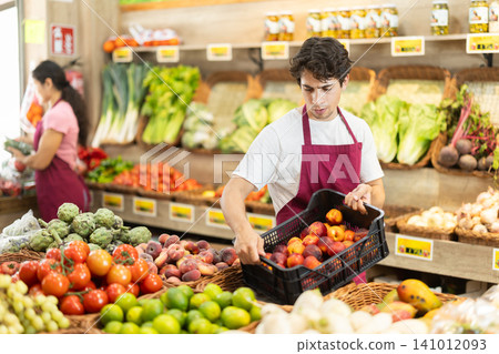 Man worker seller in grocery vegetable shop and plum Man worker seller in grocery vegetable shop and plum 141012093