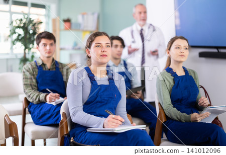 Young students in blue overalls listening to a lecture on medicine Young students in blue overalls listening to a lecture on medicine 141012096