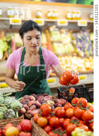 Woman worker seller in grocery vegetable shop and tomato Woman worker seller in grocery vegetable shop and tomato 141012103