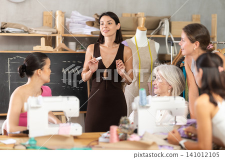 Young female teacher speaking students during dressmaking class 141012105