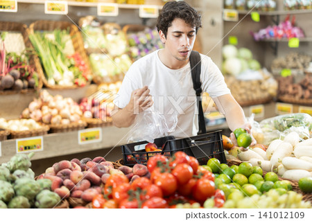 Young man choosing lime in vegetable shop Young man choosing lime in vegetable shop 141012109