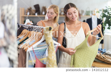 Fashionista girls friends near showcase examine goods, buying something clothing for summer. Fashionista girls friends near showcase examine goods, buying something clothing for summer. 141012112