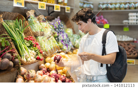 Man shopping, examine vegetable in store and buy elect onion. Man shopping, examine vegetable in store and buy elect onion. 141012113