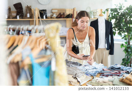 Young woman scanning qr code of jeans in clothing store Young woman scanning qr code of jeans in clothing store 141012133