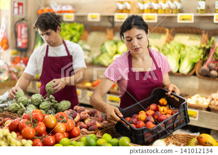 Woman worker seller in grocery vegetable shop and plum Woman worker seller in grocery vegetable shop and plum 141012134