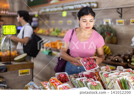 Female customer choosing vegetables and fruits in packaging at grocery store Female customer choosing vegetables and fruits in packaging at grocery store 141012200