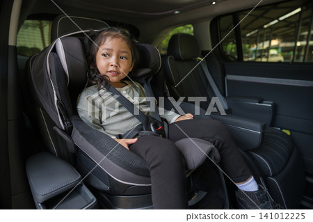 preschool child girl sitting in car seat and looking out of the window, safety baby chair travelling preschool child girl sitting in car seat and looking out of the window, safety baby chair travelling 141012225