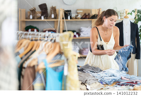 Young woman choosing denim shorts Young woman choosing denim shorts 141012232