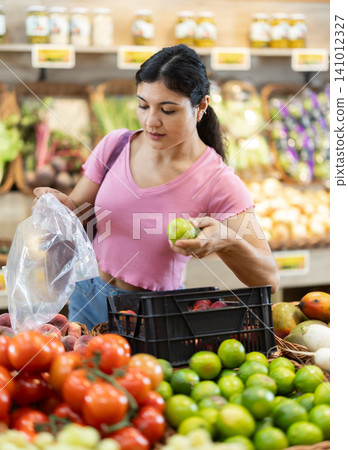Woman shopping, examine vegetable in store and buy elect lime. 141012327