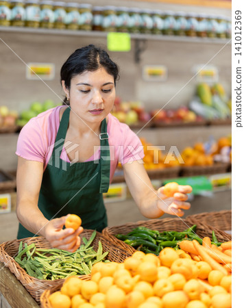 Woman worker seller in grocery vegetable shop assort fruit apricot Woman worker seller in grocery vegetable shop assort fruit apricot 141012369
