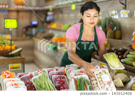 Female seller working with packaged vegetables and fruits at grocery store Female seller working with packaged vegetables and fruits at grocery store 141012408