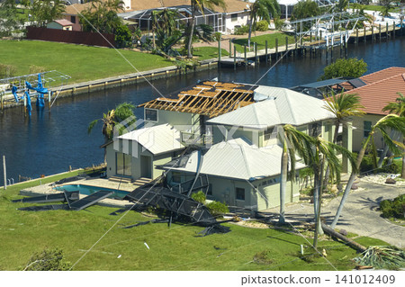 Hurricane Ian destroyed house roof in Florida residential area. Natural disaster and its consequences 141012409