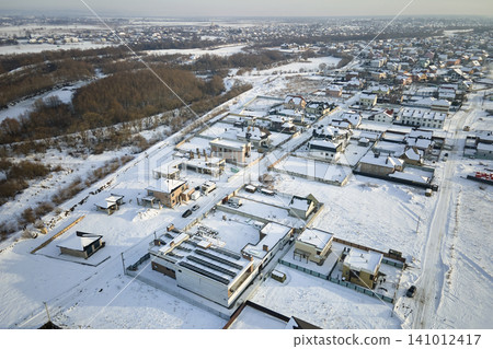Aerial view of private homes with snow covered roofs in rural suburbs town area in cold winter Aerial view of private homes with snow covered roofs in rural suburbs town area in cold winter 141012417
