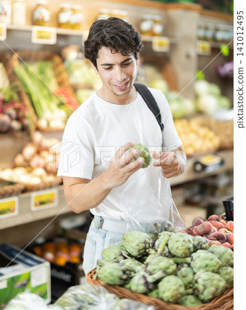 Adult man choosing artichoke in vegetable shop Adult man choosing artichoke in vegetable shop 141012495