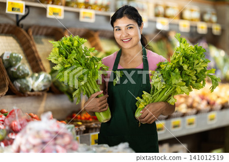 Portrait of female grocery store clerk holding celery Portrait of female grocery store clerk holding celery 141012519