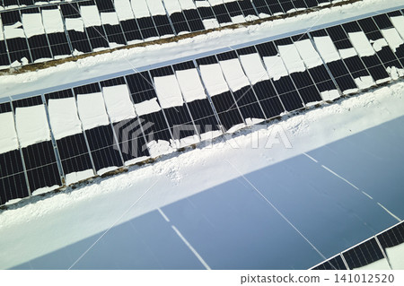 Aerial view of snow melting from covered solar photovoltaic panels at sustainable electric power plant for producing clean electrical energy. Low effectivity of renewable electricity in winter 141012520