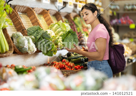 Female shopper selects fresh cabbage at grocery supermarket 141012521