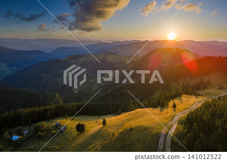 Amazing sunset scenery in wild mountain forest with old shepherd house on hillside. Dark pine woods illuminated with bright setting sun. Beautiful nature landscape Amazing sunset scenery in wild mountain forest with old shepherd house on hillside. Dark pine woods illuminated with bright setting sun. Beautiful nature landscape 141012522